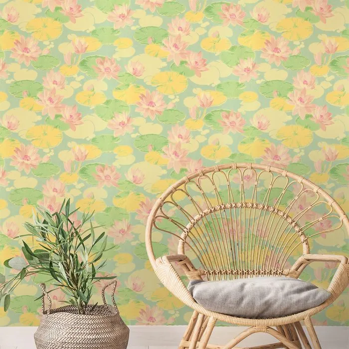 Waterlily rattan chair with gray cushion beside a potted plant, set against a yellow wall and pink-green floral vintage wallpaper—ideal for bringing charm to any set design.