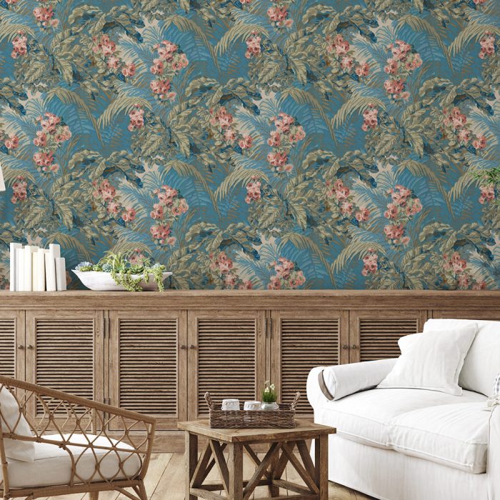 A living room featuring the Palm Garden—a blue floral wallpaper with green leaves and pink flowers—pairs with a white sofa and wooden furniture to create a charming set design.