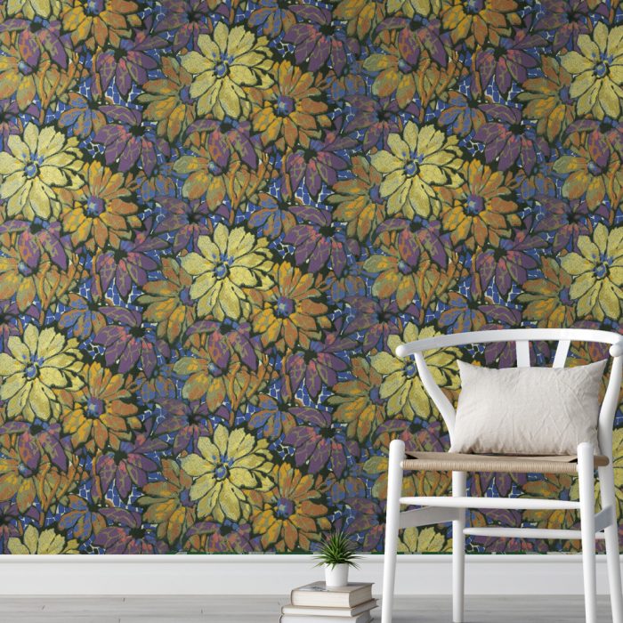 The Mosaic small white chair with a light cushion stands beside stacked books and a plant, creating an inviting scene in front of dark vintage wallpaper with yellow-orange flowers and purple leaves.