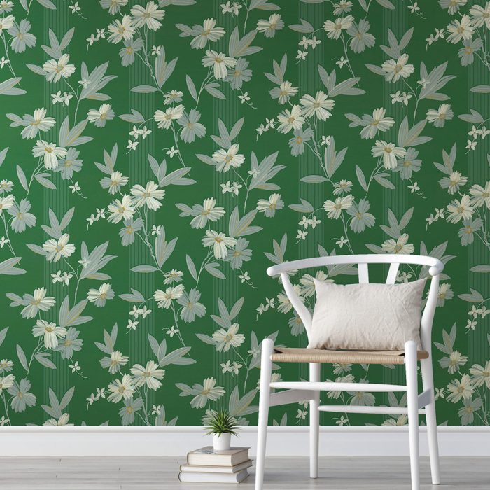 The Daisy All Day white chair with cushion sits beside stacked books in front of vintage-style wallpaper, creating an inviting set design against a green floral-patterned wall.